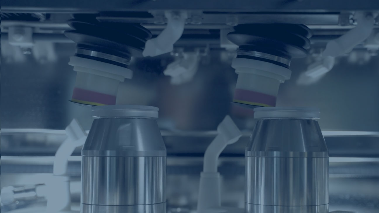 Close-up of dual polishing heads processing glass lenses inside an industrial machine.